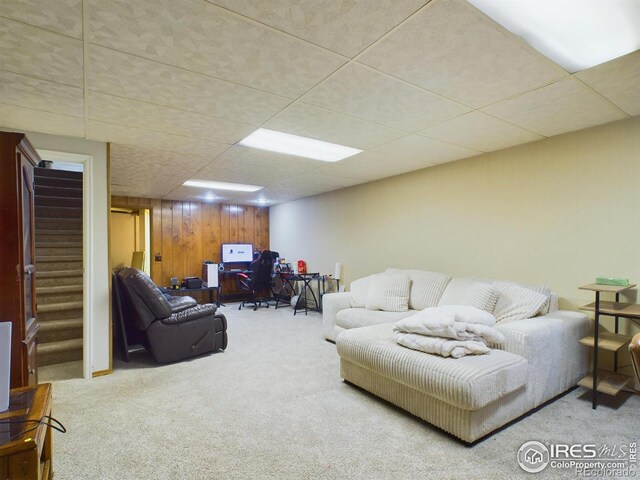 carpeted living room with wood walls and a paneled ceiling