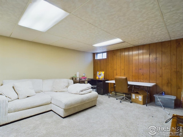 living area featuring a paneled ceiling, wood walls, and carpet