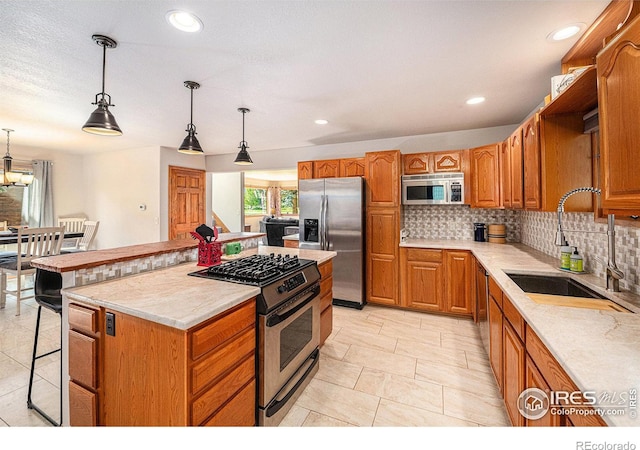 kitchen with a kitchen island, sink, decorative backsplash, hanging light fixtures, and stainless steel appliances