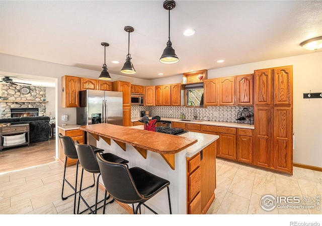 kitchen with appliances with stainless steel finishes, decorative light fixtures, sink, a kitchen bar, and a center island