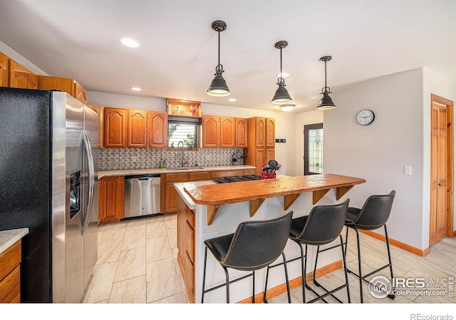 kitchen with sink, stainless steel appliances, a center island, decorative backsplash, and decorative light fixtures