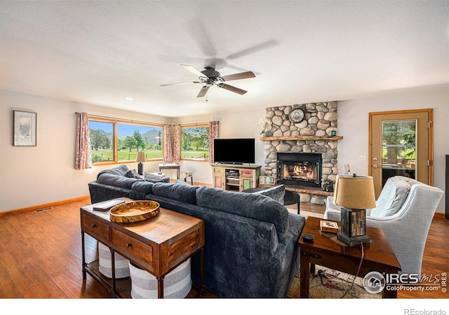 living room with ceiling fan, a stone fireplace, and dark hardwood / wood-style flooring