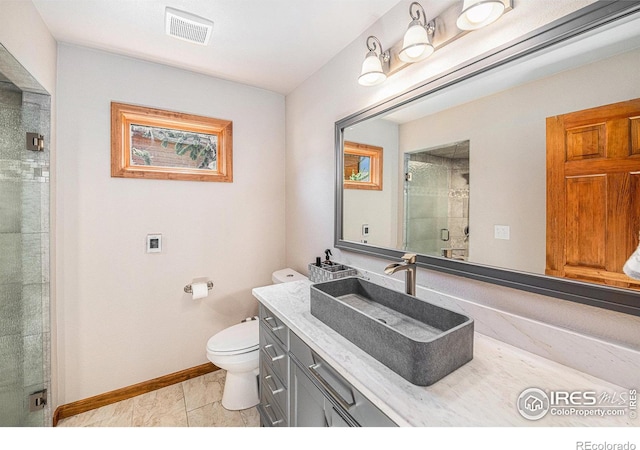 bathroom with a shower with door, vanity, tile patterned flooring, and toilet