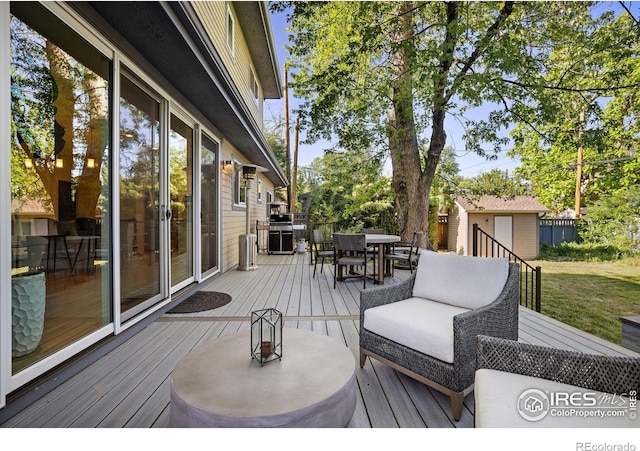 wooden terrace with a storage unit and a grill