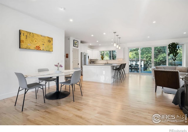 dining space with light wood-type flooring and sink