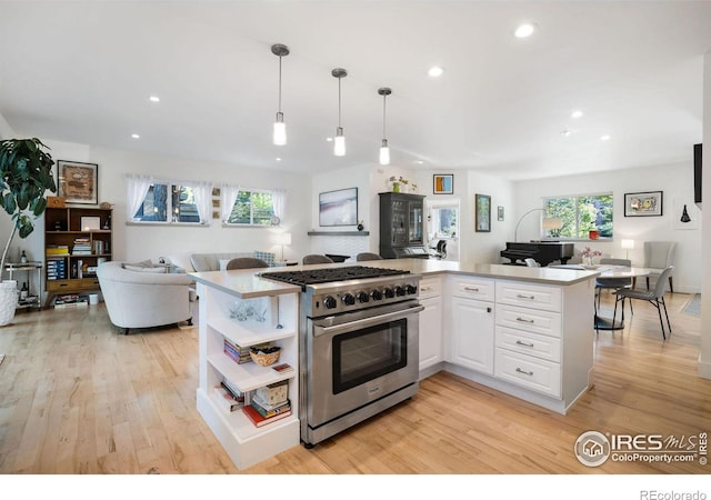 kitchen featuring white cabinetry, hanging light fixtures, light hardwood / wood-style flooring, high end stove, and kitchen peninsula