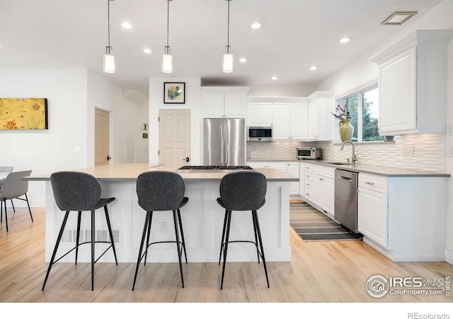 kitchen featuring white cabinets, pendant lighting, a center island, and stainless steel appliances