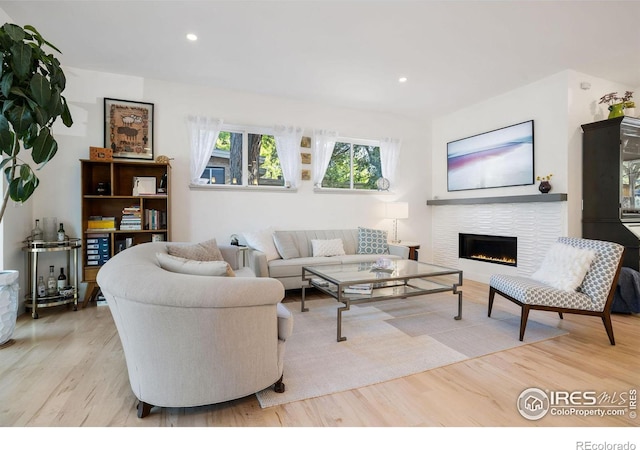 living room with light wood-type flooring and a tile fireplace