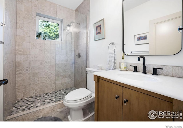 bathroom featuring tile patterned floors, vanity, toilet, and tiled shower