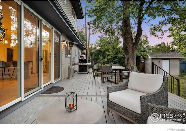 deck at dusk featuring a storage shed