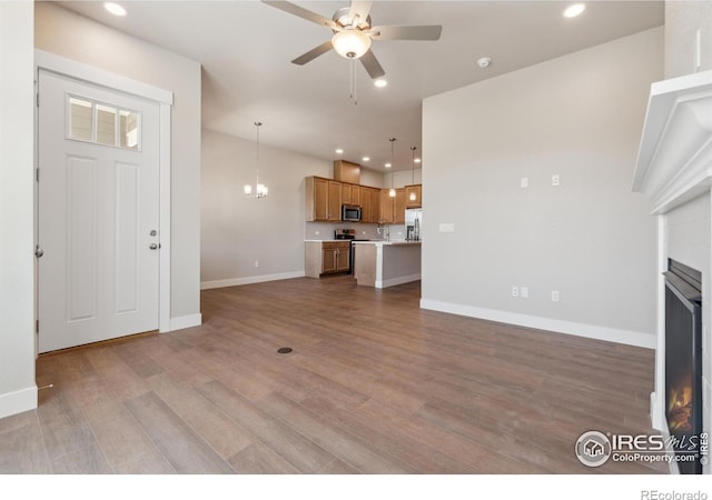 unfurnished living room featuring ceiling fan, light hardwood / wood-style floors, and sink