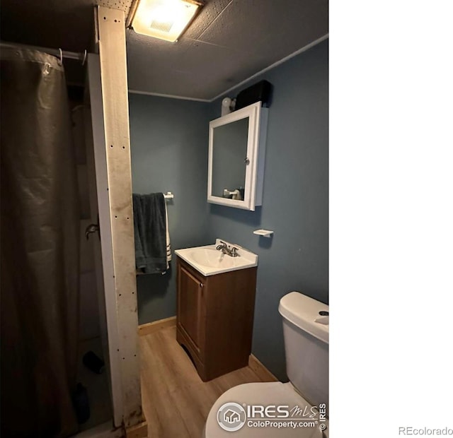 full bath featuring toilet, a shower with shower curtain, wood finished floors, and vanity