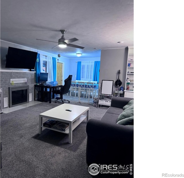 living area with a fireplace with flush hearth, ceiling fan, carpet, a textured ceiling, and built in shelves