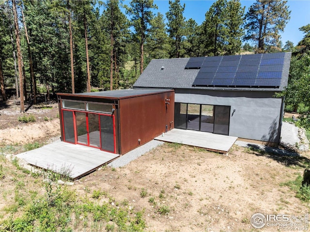 rear view of property with solar panels and a sunroom