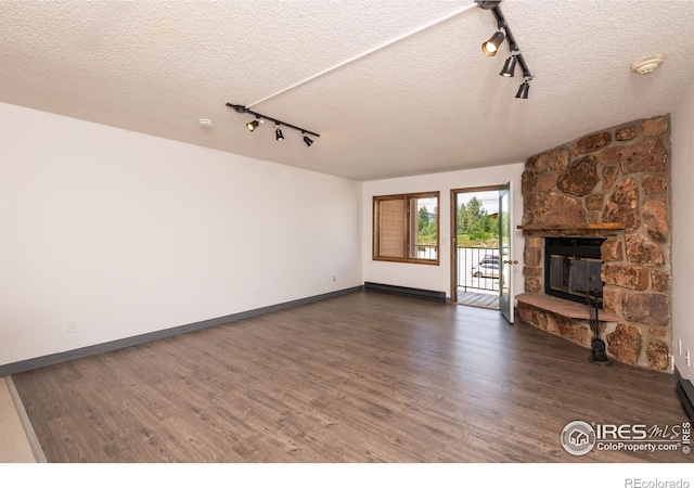 unfurnished living room with dark wood-type flooring, a fireplace, a baseboard radiator, and a textured ceiling