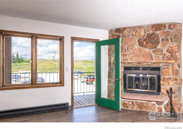 doorway with a stone fireplace, dark wood-type flooring, a textured ceiling, and baseboard heating