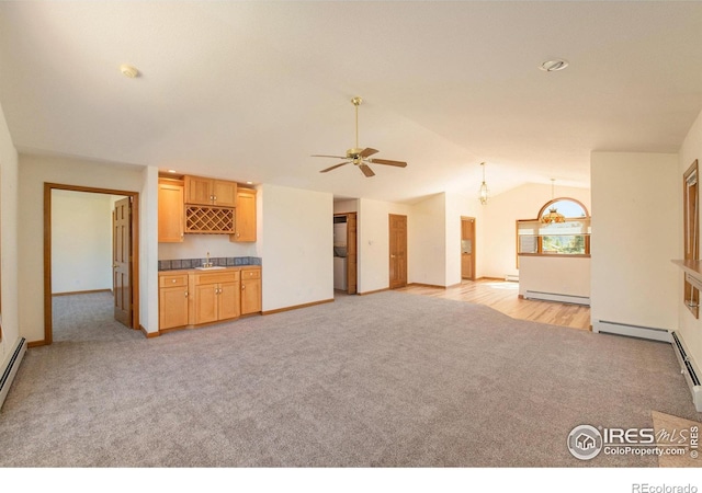 unfurnished living room featuring lofted ceiling, a baseboard heating unit, sink, ceiling fan, and light colored carpet