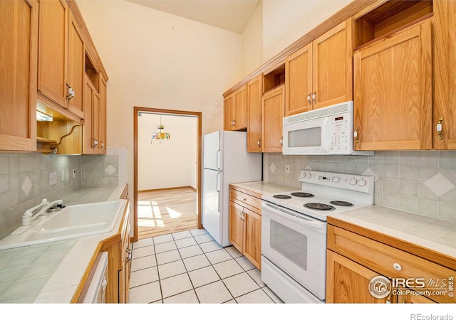 kitchen with tasteful backsplash, tile countertops, sink, and white appliances