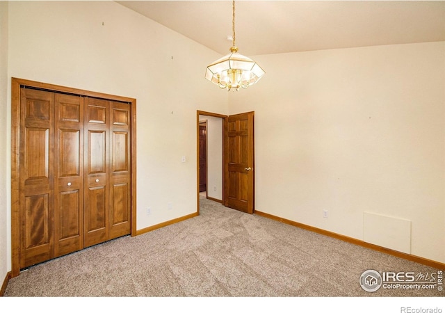 unfurnished bedroom with a closet, light colored carpet, a chandelier, and lofted ceiling