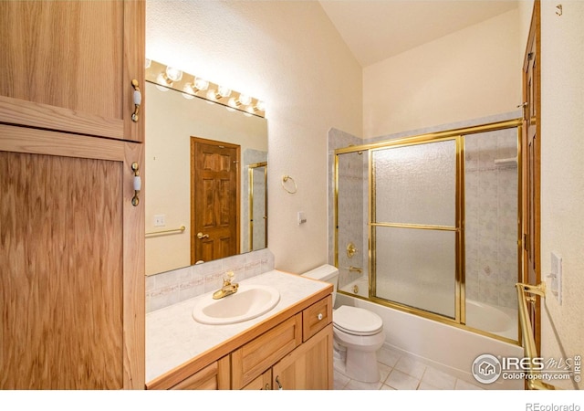 full bathroom featuring combined bath / shower with glass door, vanity, vaulted ceiling, tile patterned flooring, and toilet