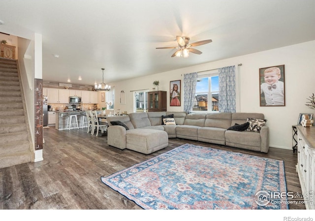 living room featuring dark wood-type flooring and ceiling fan with notable chandelier