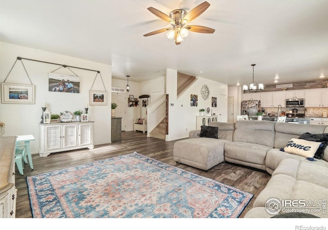 living room with ceiling fan with notable chandelier, dark hardwood / wood-style floors, and sink