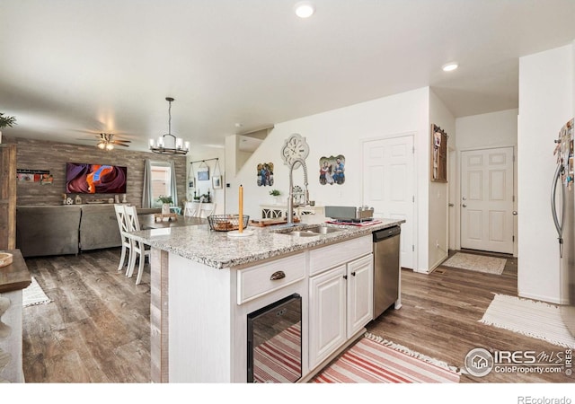 kitchen with stainless steel dishwasher, beverage cooler, sink, a center island with sink, and hanging light fixtures