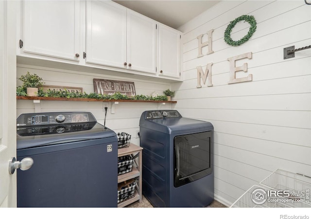 washroom with wood walls, cabinets, and washing machine and clothes dryer