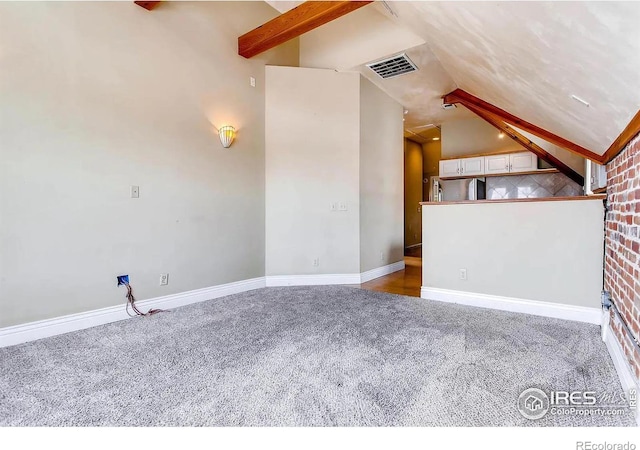 unfurnished living room featuring lofted ceiling with beams and light carpet