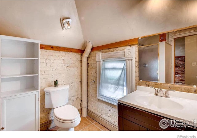 bathroom featuring tile patterned flooring, vanity, toilet, and brick wall