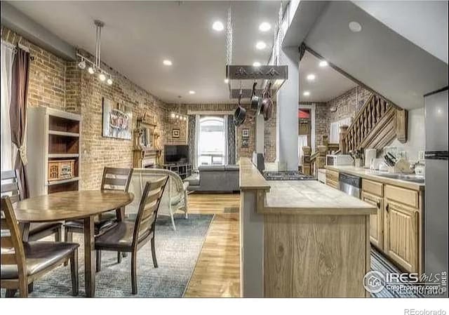 kitchen featuring dishwasher, light wood-type flooring, a kitchen island, and brick wall