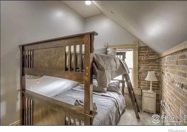 bedroom with brick wall and vaulted ceiling