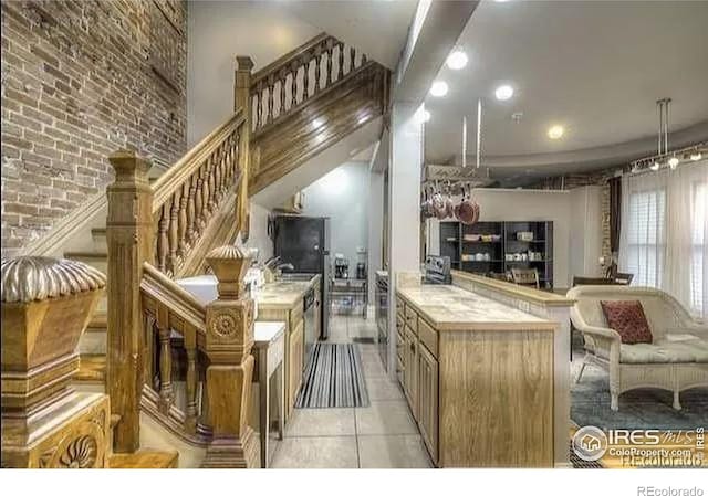 kitchen featuring kitchen peninsula, light tile patterned flooring, and brick wall