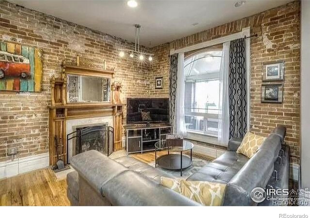 living room featuring hardwood / wood-style floors, a large fireplace, and brick wall