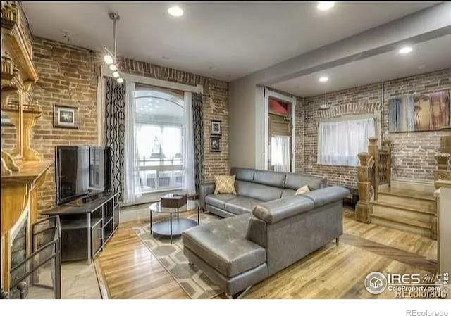 living room featuring brick wall and light hardwood / wood-style floors