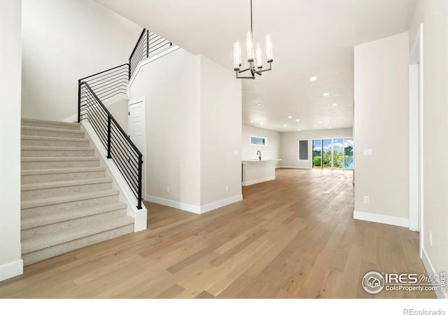 unfurnished living room with a chandelier and light hardwood / wood-style floors