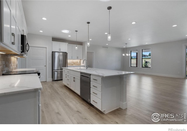 kitchen with a kitchen island with sink, stainless steel appliances, decorative backsplash, sink, and white cabinetry