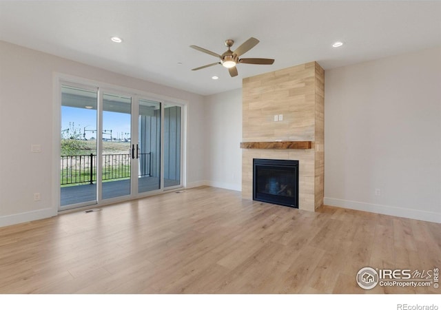 unfurnished living room with ceiling fan, light wood-type flooring, and a tile fireplace