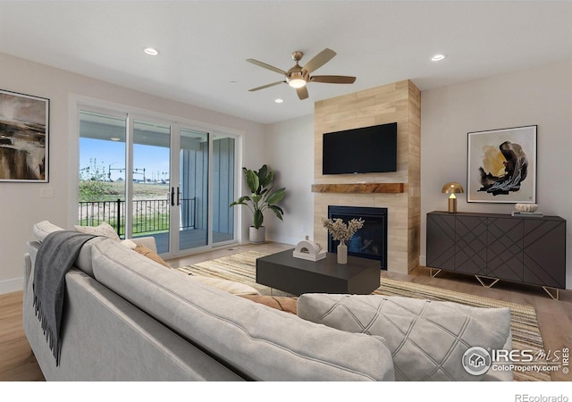 living room featuring light hardwood / wood-style floors, ceiling fan, and a fireplace