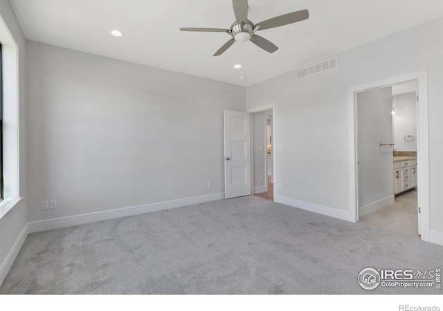 unfurnished bedroom with ensuite bathroom, light carpet, and ceiling fan