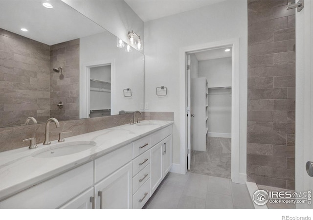 bathroom featuring a tile shower, tile patterned floors, and vanity