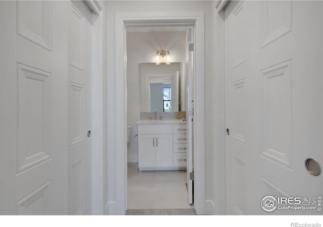 corridor featuring light tile patterned flooring and sink