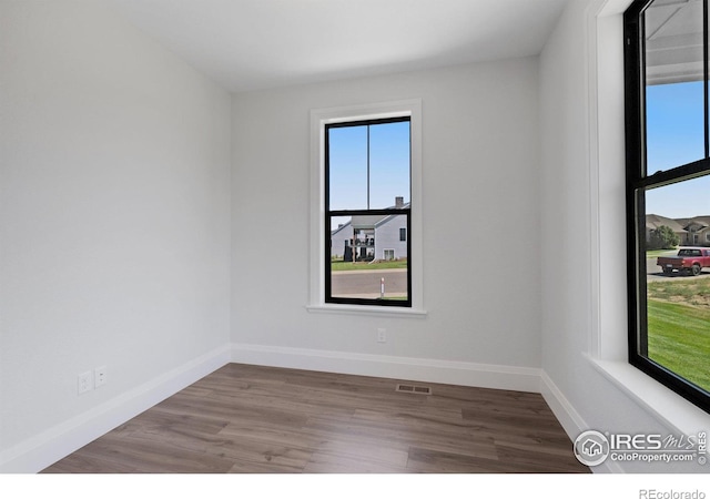 spare room with hardwood / wood-style flooring and a healthy amount of sunlight