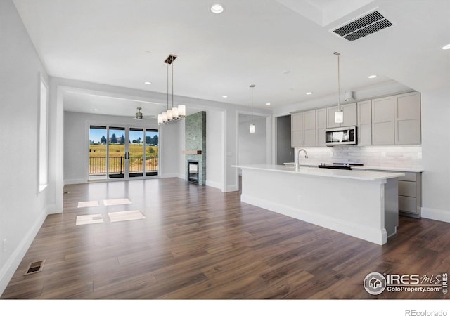 kitchen featuring a large island with sink, gray cabinetry, hanging light fixtures, and dark hardwood / wood-style floors