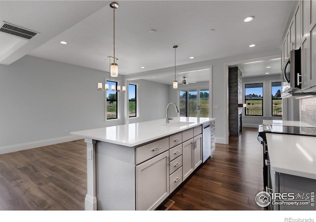 kitchen featuring stainless steel appliances, an island with sink, ceiling fan, pendant lighting, and sink