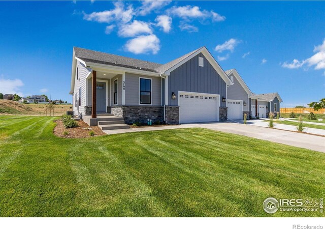 5700 2nd Street Rd, Greeley, CO 80634 - view of front of house featuring an attached garage, driveway, a front yard, board and batten siding, and stone siding