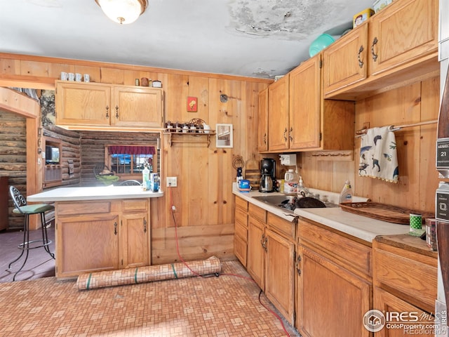 kitchen with a breakfast bar, wood walls, sink, and log walls