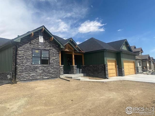 view of front of house with board and batten siding, driveway, stone siding, and a garage