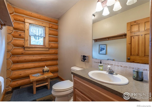 bathroom with tasteful backsplash, toilet, vanity, and rustic walls