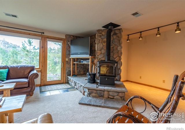 living room with a wood stove, carpet, and rail lighting